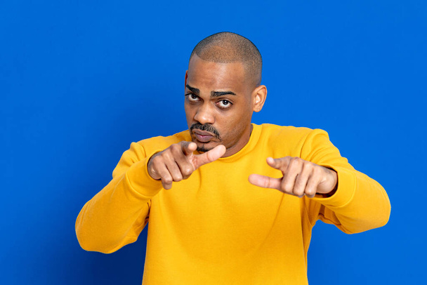 Afrikaan met een gele trui op een blauwe achtergrond - Foto, afbeelding