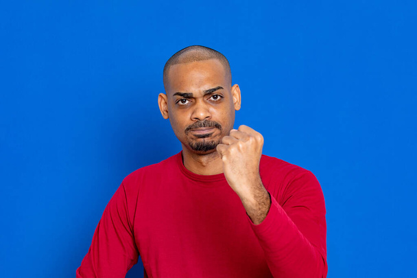 Africano con un jersey rojo sobre un fondo azul
 - Foto, imagen