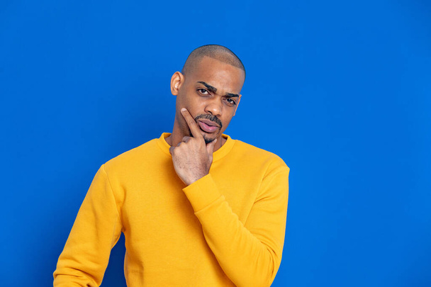 African guy with a yellow jersey on a blue background - Foto, Imagen