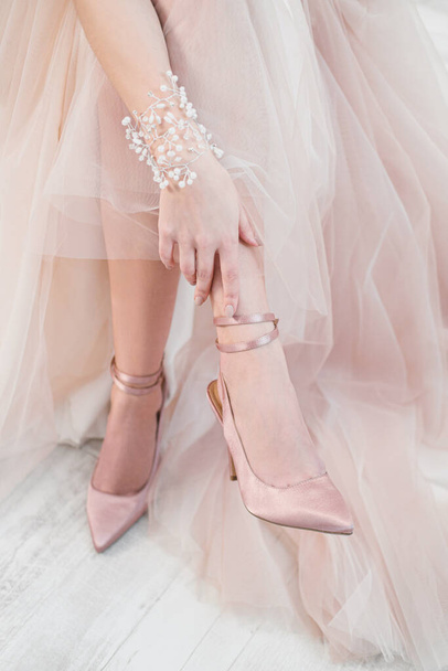 The woman bride puts shoes on her leg. Wedding dress and shoes. - Foto, Bild