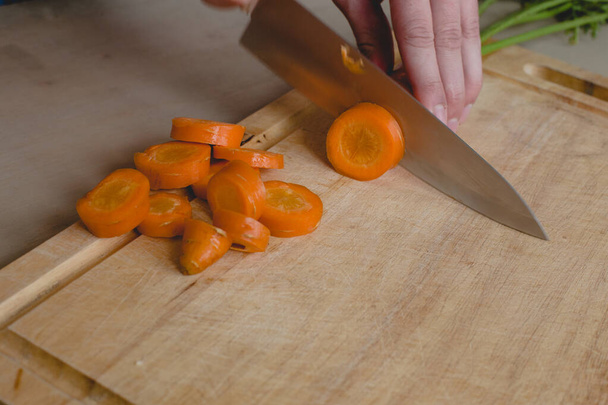 Food, natural. Guy cuts carrot - Photo, Image