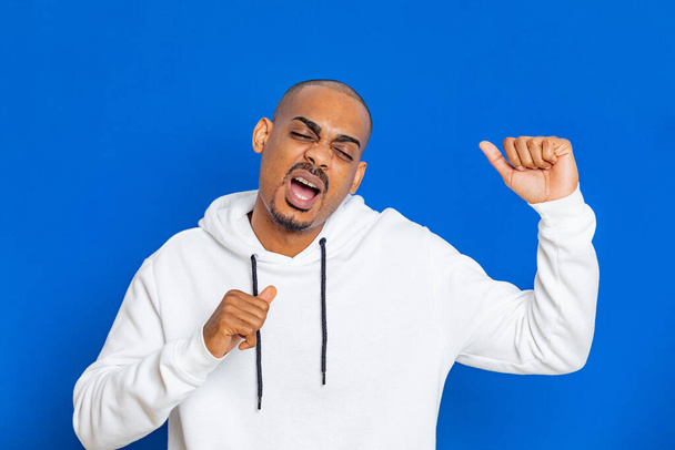 African guy wearing a white sweatshirt on a blue background - Photo, Image