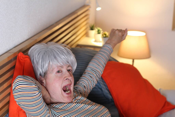 mature femme aux cheveux gris étirement tout en se relaxant au lit pendant l'isolement à la maison
 - Photo, image