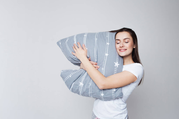 Sleep and drowsiness, a young woman hugs a pillow and sleeps standing up - Foto, immagini