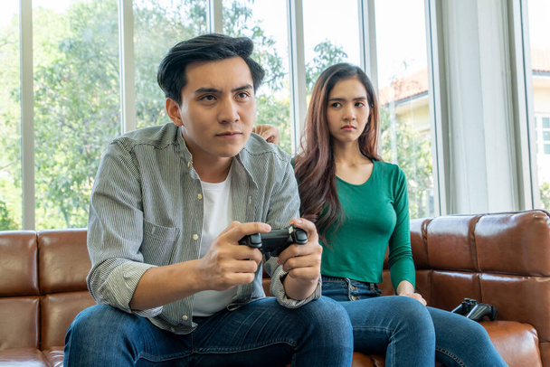 Młoda azjatycka para cierpi na uzależnienie od gier komputerowych. Koncepcja problemu rodzinnego. - Zdjęcie, obraz