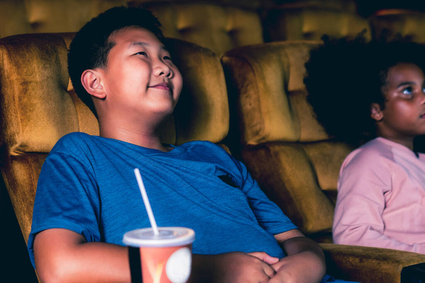 Tres niños divirtiéndose y disfrutando viendo películas en el cine - Foto, imagen