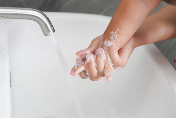 Matka umyjte dětskou ručičku pro prevenci románu Coronavirus nemoc 2019 nebo COVID-19. Lidé myjí ruce v koupelně umyvadlo vyčistit virus infekce. - Fotografie, Obrázek