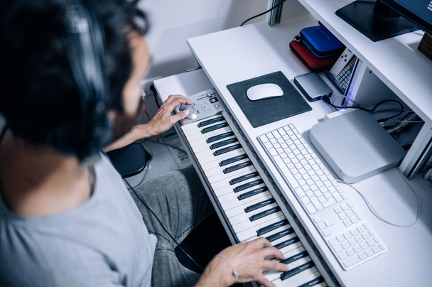 Vista superior del músico tocando piano eléctrico en el estudio de grabación casero.Escritorio del músico. Música, concepto de e-learning
 - Foto, imagen