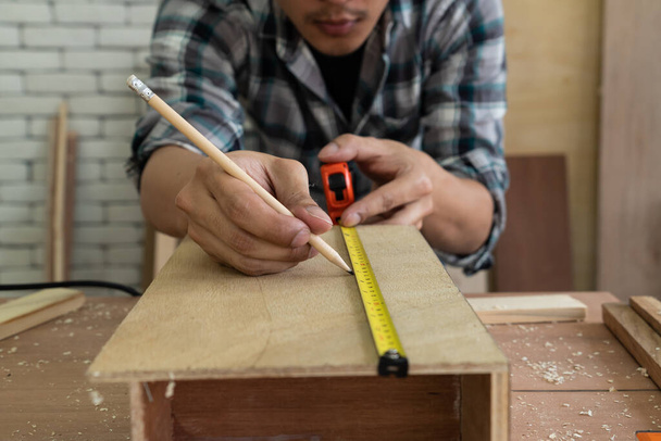 Menuisier travaillant sur l'artisanat en bois à l'atelier pour produire des matériaux de construction ou des meubles en bois. Le jeune menuisier asiatique utilise des outils professionnels pour l'artisanat. Bricoleur et menuiserie concept de travail. - Photo, image