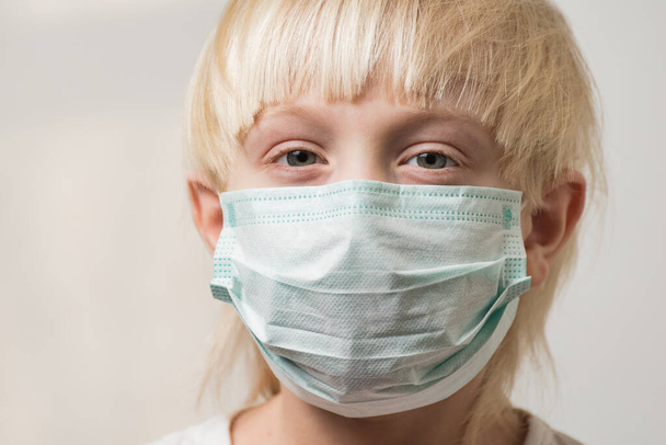 Blond jongetje met masker om ziektekiemen te voorkomen. Bescherming tegen influenzavirus. Covidiënt 19. - Foto, afbeelding