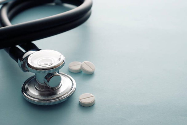 Таблетки или таблетки, лежащие рядом со стетоскопом на белом фоне с копировальным пространством концептуальной медицины, здравоохранения и медикаментозного лечения
 - Фото, изображение