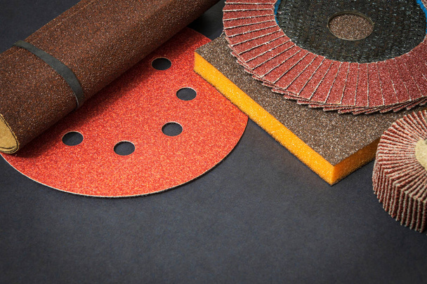 Big set of abrasive tools and multicolored sandpaper on black background, wizard is used for grinding items - Photo, Image