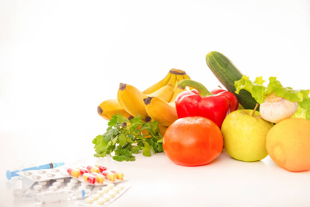 fresh fruits and vegetables, medicines on a white background, tomato, bananas, herbs, Apple, pepper, cucumber, lemon, tablets, syringe, - Valokuva, kuva