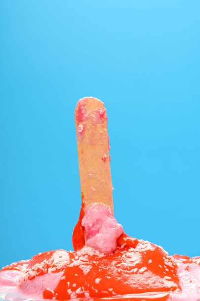 red popsicle with shredded coconut melted on a blue background - Foto, Imagem