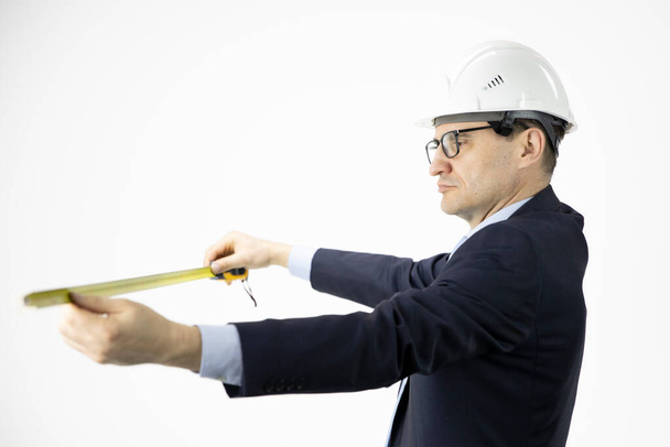 Architect in hard hat measures with tape measure on isolated white background - Photo, Image