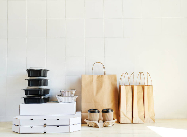 many takeaway paper bags and containers on table in white bright room. Takeout meal - 写真・画像