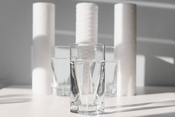 Concept Household filtration system. water treatment concept. use of water filters at home. Glasses of clean water and filters on a white background - Fotoğraf, Görsel