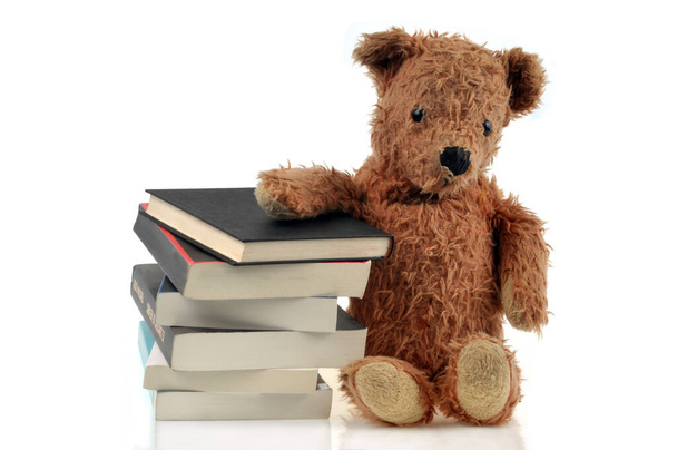 Teddybär neben einem Stapel Bücher in Großaufnahme auf weißem Hintergrund - Foto, Bild