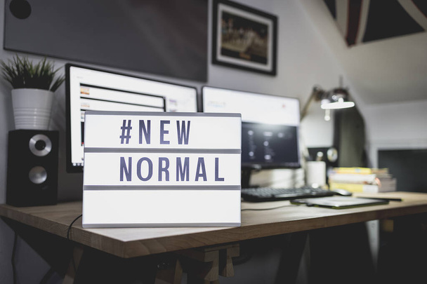 作業机の上のテキストハッシュタグ#NEW NORMALでライトサイン。家から仕事だ。新しい通常の概念。社会的距離. - 写真・画像
