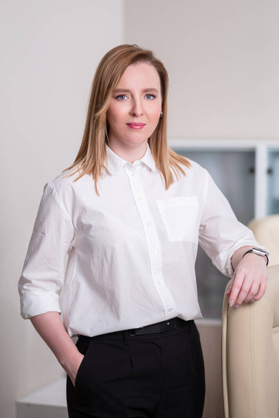 Portrait of a young beautiful woman, an office employee in a white shirt. A woman works at a computer. - Foto, Bild