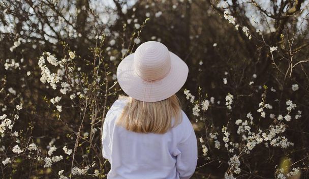 A blonde woman wearing a white hat with trees on the background - Foto, immagini