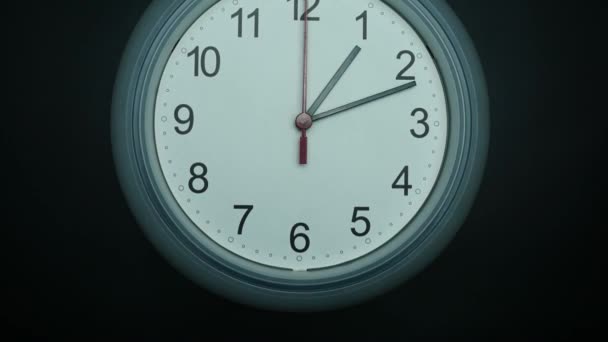Zamknij Kamera kątowa od dołu do góry, Biały zegar ścienny izolowany 01.00 lub pm. na czarnym tle. - Materiał filmowy, wideo