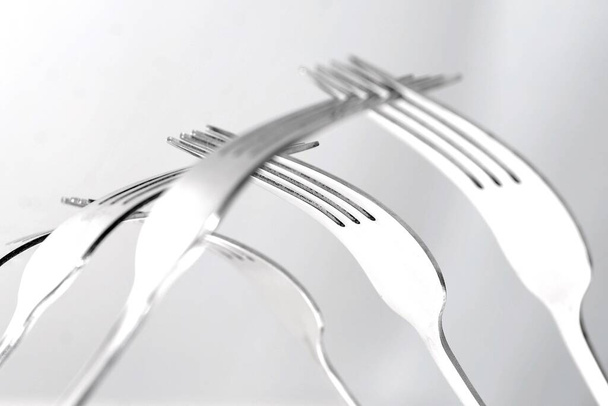 A selective focus shot of table forks fitted into each other against a grey background - Foto, imagen
