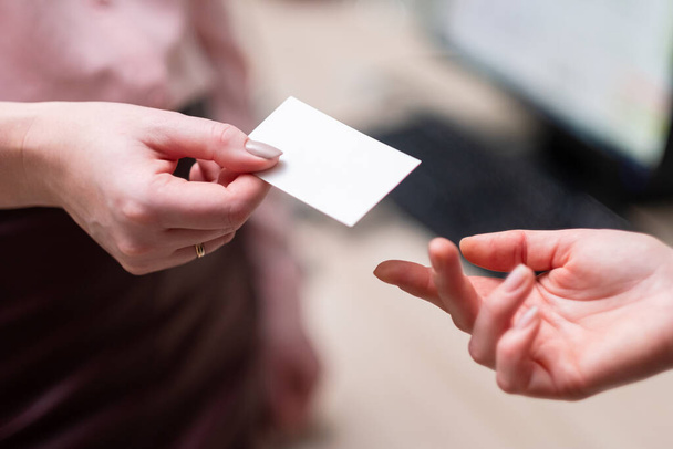A woman gives another woman a business card. A close-up of two hands. - Foto, Imagen