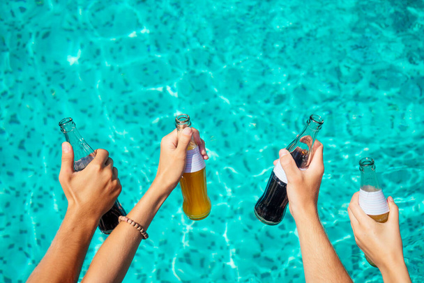 best friends drinking lemonade while refreshing in the swimmingpool hands close up on blue aquamarine color background - Valokuva, kuva