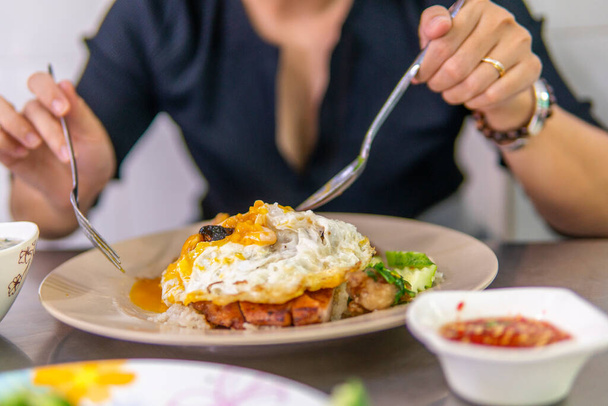a girl eating Com tam - a Vietnamese broken rice with pickles steak grilled pork ribs cucumber onion oil sweet chilies garlic fish sauce fried egg omelet Asian cuisine. a popular breakfast in Vietnam - Photo, image