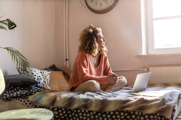 Young woman working in bed at home with laptop - Fotoğraf, Görsel