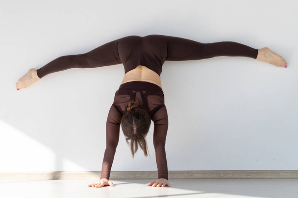 Une fille en survêtement se tient sur ses mains dans un studio de yoga léger
 - Photo, image