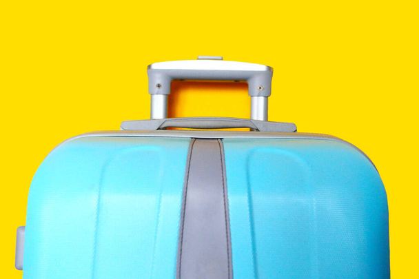 Μπλε βαλίτσα απομονωμένη στο κίτρινο. Ταξιδιωτική ιδέα, banner, closeup - Φωτογραφία, εικόνα