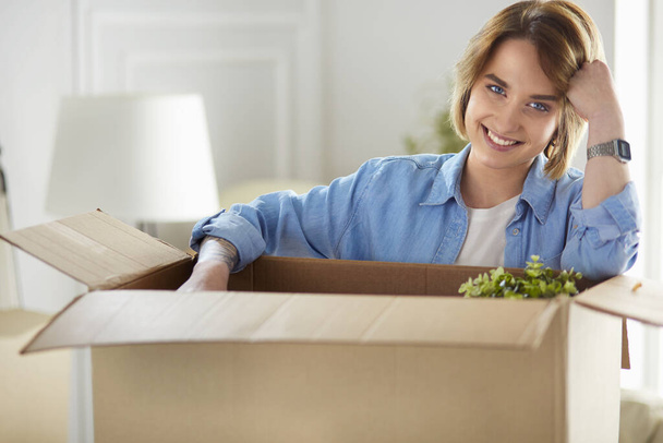 A beautiful single young woman unpacking boxes and moving into a new home - Foto, afbeelding