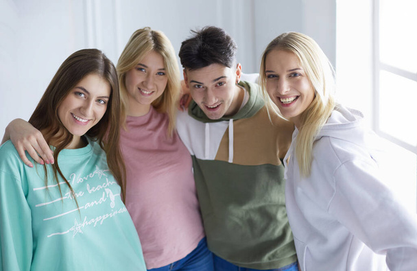 Happy smiling friends, group of young people standing and embracing together - Фото, изображение