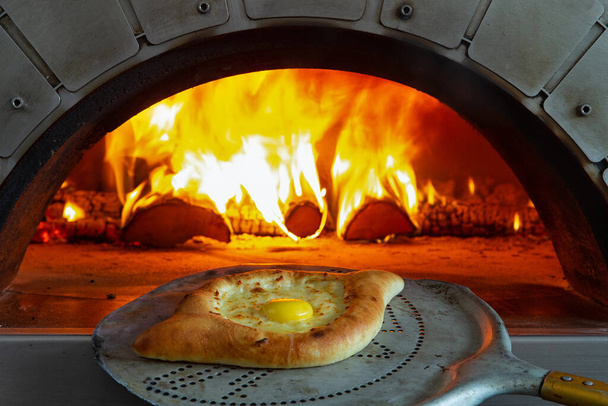 A traditional cheese pie is taken out of the oven. - Photo, Image