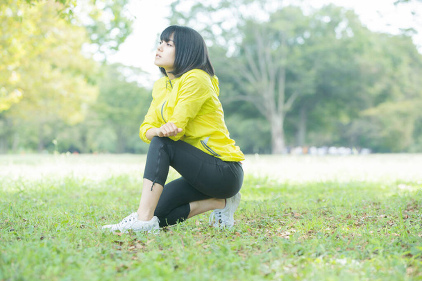 Asiática (japonesa) joven mujer estirándose en un parque lleno de vegetación
 - Foto, imagen