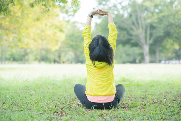Азійська (японська) молода жінка, що тягнеться в парку, наповненому зеленню. - Фото, зображення