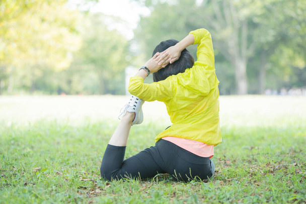 Aziatisch (Japans) jonge vrouw stretching in een park vol groen - Foto, afbeelding
