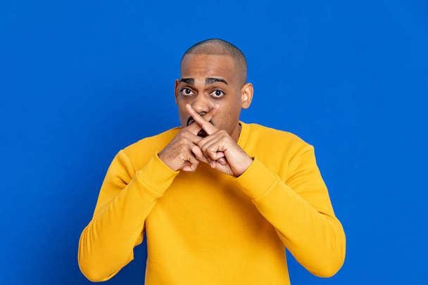 Afrikaan met een gele trui op een blauwe achtergrond - Foto, afbeelding