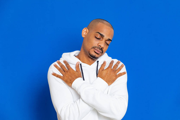 African guy wearing a white sweatshirt on a blue background - Fotó, kép
