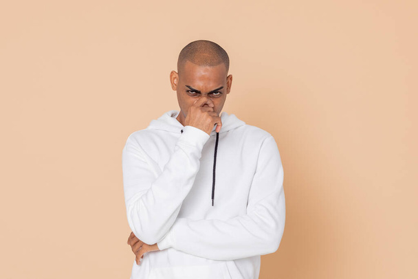 Pensive African guy with a white sweatshirt on a yellow background - Photo, Image