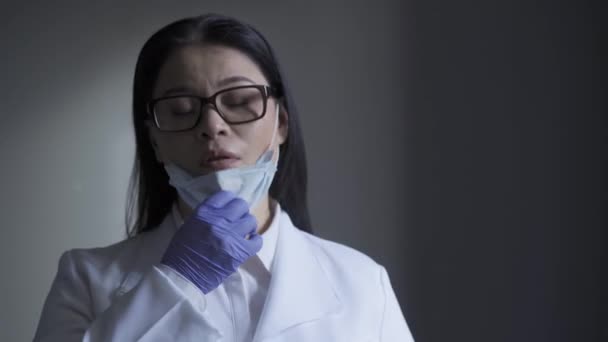 The doctor takes a sigh of relief by removing the mask from his face. Female doctor tired during coronavirus pandemic. Prores 422 - Séquence, vidéo