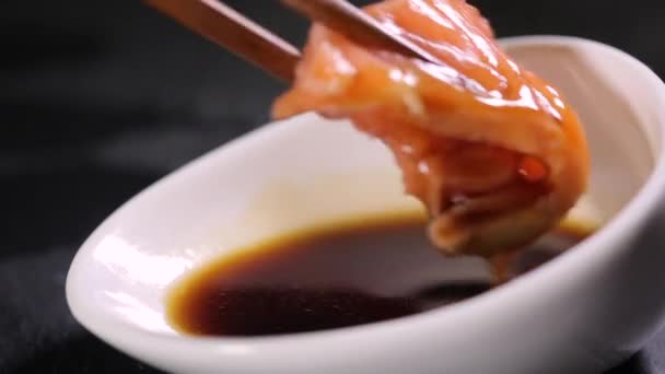 Muž bere červené ryby lososa z omáčkou loď s japonskou chopstic - Záběry, video