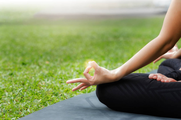 Asiatin praktiziert Yoga in Root Bond, Mula Bandha posiert auf der Matte im Outdoor-Park. - Foto, Bild