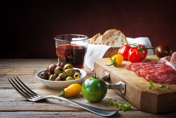 Сельский закуски, салями, оливки, помидоры и красное вино
. - Фото, изображение