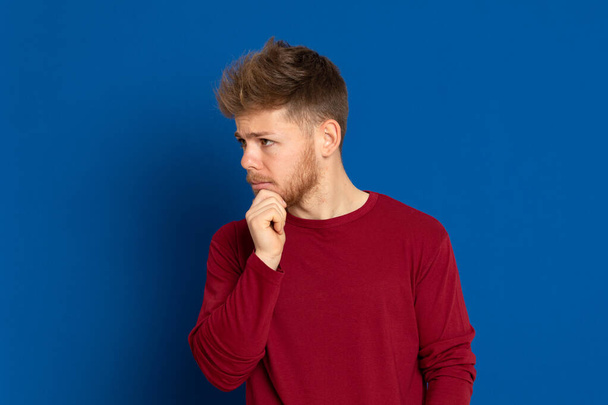 Atractivo joven con una camiseta roja sobre un fondo azul
 - Foto, imagen