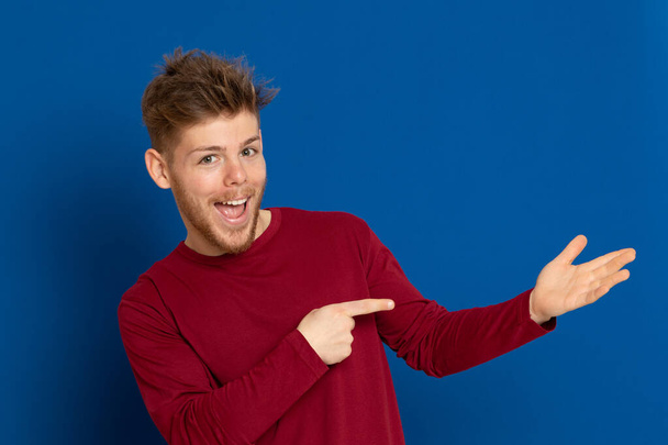 Attractive young guy with a red T-shirt on a blue background - Fotoğraf, Görsel