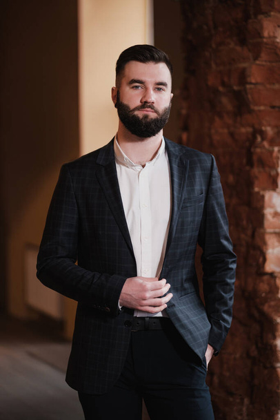 A young handsome man with a beard in a business suit in the interior of a restaurant. - Zdjęcie, obraz