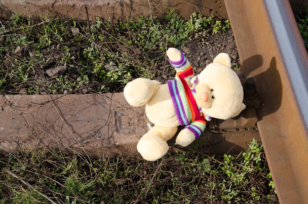 Teddy beer in een kleurrijke trui ligt op de slapers - Foto, afbeelding
